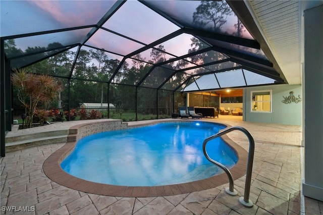 pool at dusk featuring a patio area, an outdoor hangout area, and glass enclosure