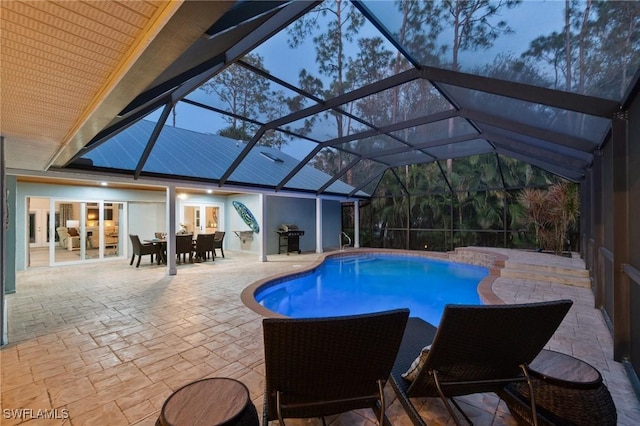 pool at dusk featuring a grill, a lanai, and a patio area