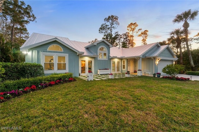 view of front of property with french doors, a garage, and a yard