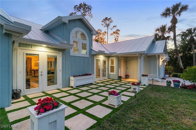 back house at dusk featuring french doors, a yard, and a patio