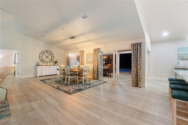 dining space with vaulted ceiling and light hardwood / wood-style floors