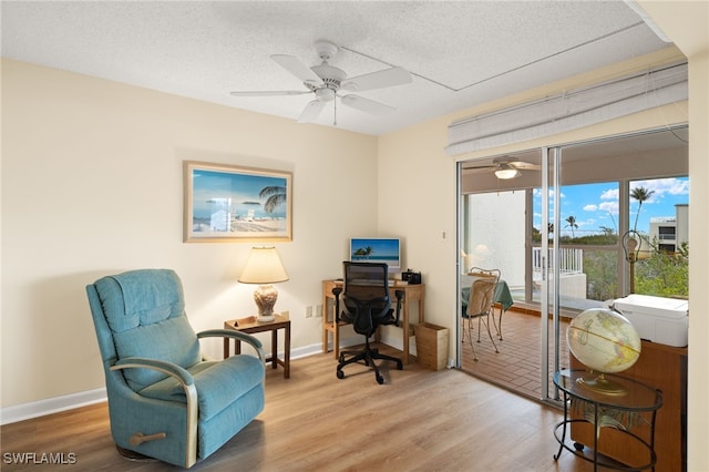 home office featuring a textured ceiling, baseboards, and wood finished floors