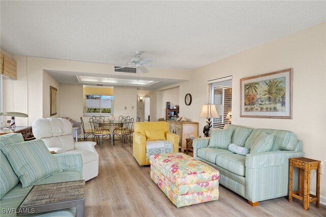 living area featuring light wood-style flooring, visible vents, and a ceiling fan