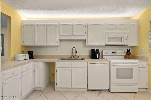 kitchen featuring white appliances, light countertops, a sink, and white cabinetry