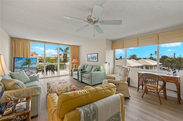 living room featuring ceiling fan, light wood-style flooring, and a textured ceiling