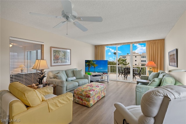 living room featuring expansive windows, ceiling fan, a textured ceiling, and light wood-style flooring