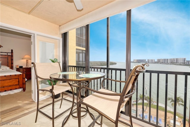 sunroom / solarium with a water view and ceiling fan