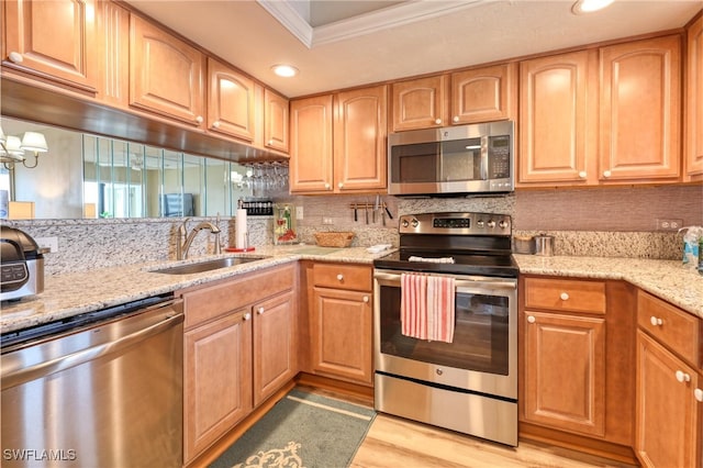 kitchen featuring crown molding, appliances with stainless steel finishes, sink, light wood-type flooring, and light stone counters