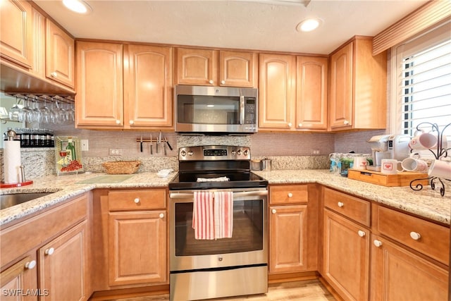 kitchen featuring stainless steel appliances, light stone countertops, and backsplash