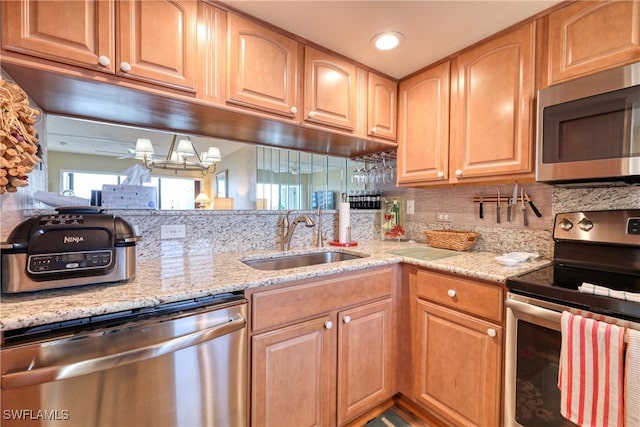 kitchen with sink, backsplash, light stone countertops, and appliances with stainless steel finishes