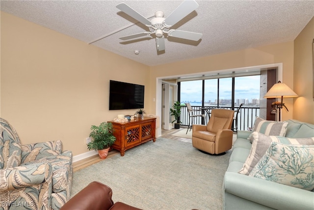 living room with a textured ceiling, light hardwood / wood-style flooring, and ceiling fan