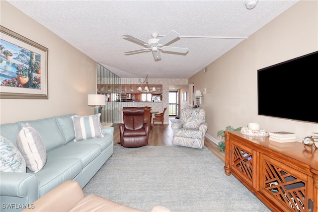 carpeted living room featuring ceiling fan and a textured ceiling