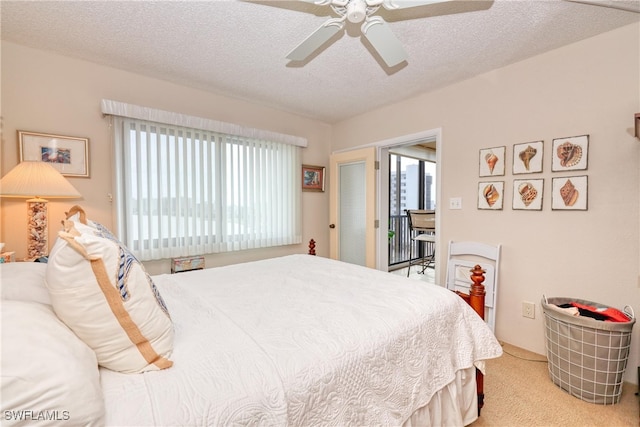 bedroom featuring light carpet, a textured ceiling, and ceiling fan