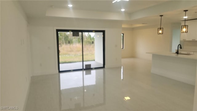 kitchen with pendant lighting, a raised ceiling, sink, white cabinets, and light tile patterned flooring