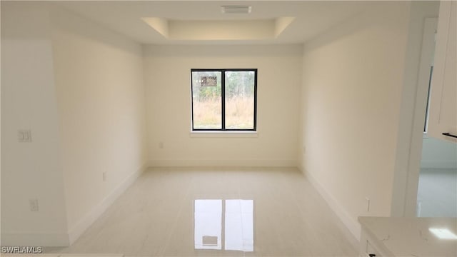 spare room featuring light tile patterned flooring and a tray ceiling