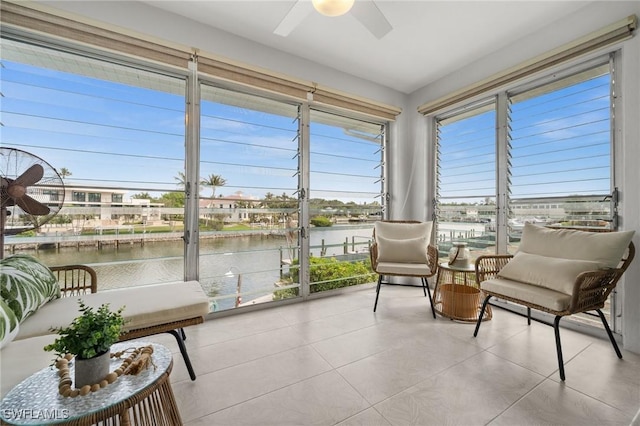 sunroom with ceiling fan and a water view