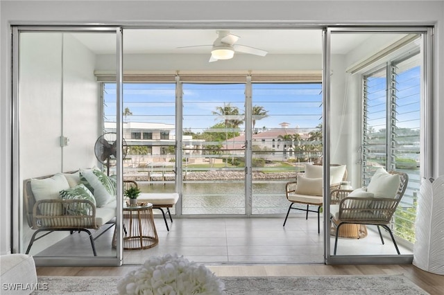 sunroom / solarium with a water view and ceiling fan