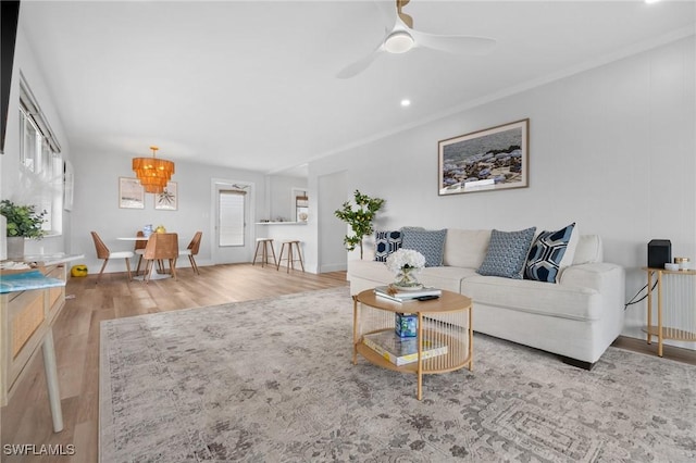 living room with light hardwood / wood-style floors, crown molding, ceiling fan, and a healthy amount of sunlight