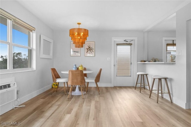 dining space featuring light wood-type flooring, an inviting chandelier, and washer / dryer