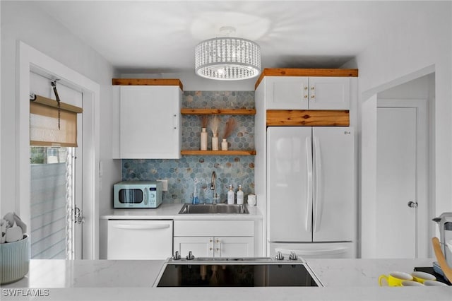 kitchen with white appliances, white cabinets, decorative backsplash, sink, and a chandelier