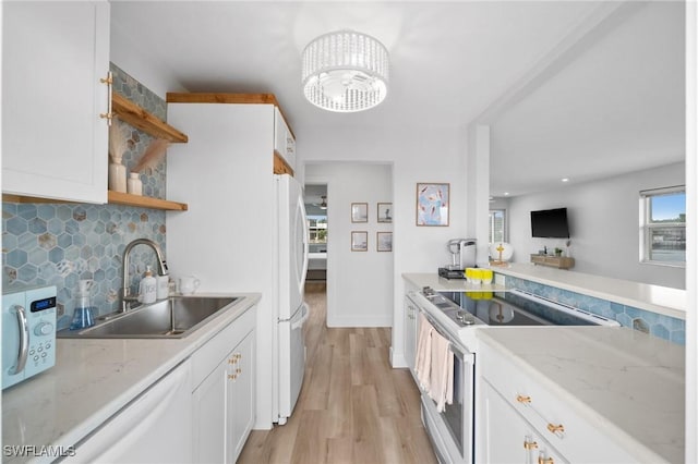 kitchen with light stone countertops, white appliances, white cabinetry, and sink