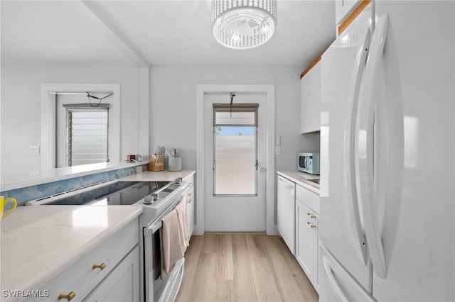 kitchen with white cabinetry, light stone countertops, white appliances, and light wood-type flooring