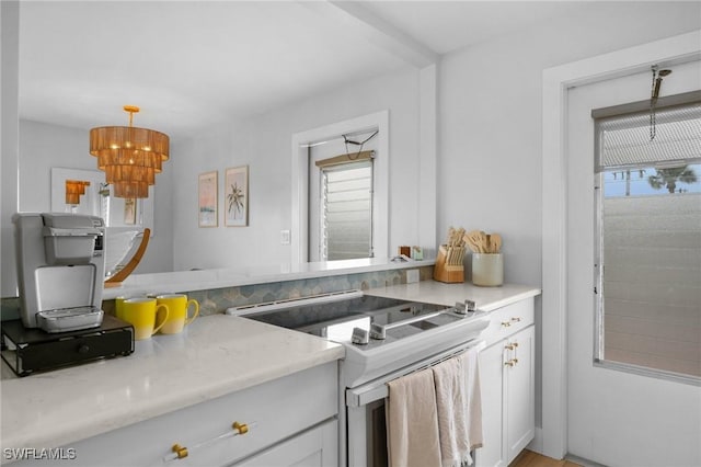 kitchen featuring decorative light fixtures, a healthy amount of sunlight, white cabinets, and electric stove