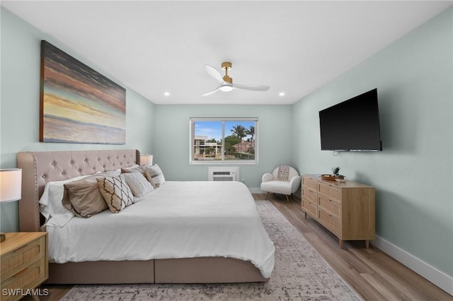 bedroom featuring ceiling fan, light wood-type flooring, and an AC wall unit