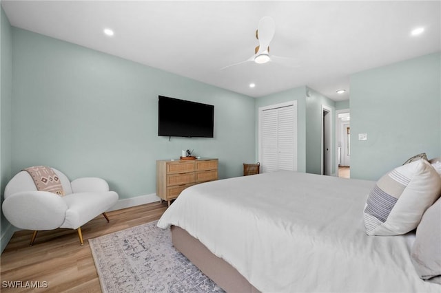 bedroom with ceiling fan, light hardwood / wood-style flooring, and a closet