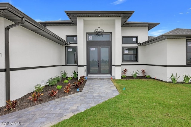 view of exterior entry featuring a lawn and french doors