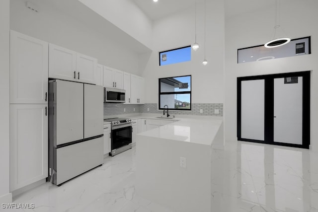 kitchen featuring decorative light fixtures, refrigerator, kitchen peninsula, and stainless steel electric range oven