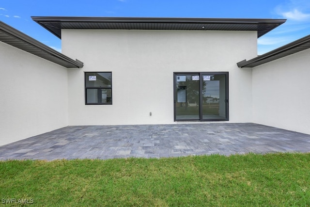 back of house with a patio area and a lawn