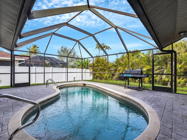 view of pool featuring a grill, a patio, and glass enclosure