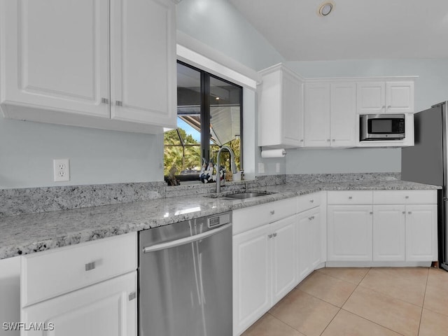 kitchen with sink, light tile patterned flooring, white cabinetry, appliances with stainless steel finishes, and light stone counters