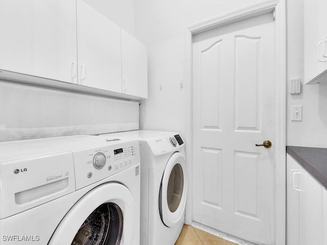 washroom with light tile patterned flooring, independent washer and dryer, and cabinets