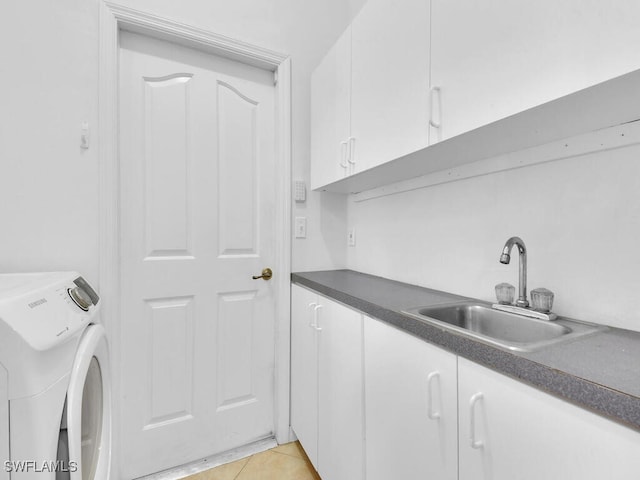 washroom with light tile patterned floors, sink, washer / dryer, and cabinets