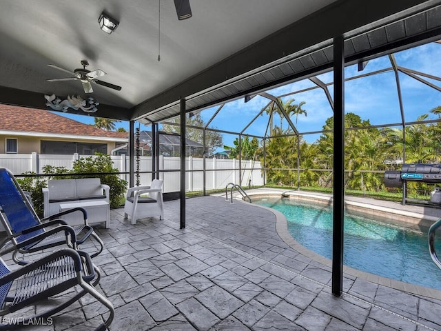 view of pool featuring ceiling fan, glass enclosure, an outdoor living space, and a patio