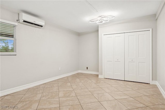 unfurnished bedroom featuring an AC wall unit, light tile patterned floors, and a closet