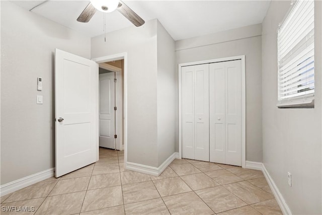 unfurnished bedroom with light tile patterned flooring, ceiling fan, and a closet