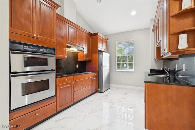 kitchen with appliances with stainless steel finishes, dark stone countertops, sink, backsplash, and vaulted ceiling