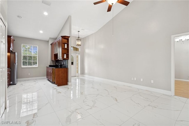 kitchen with high vaulted ceiling, decorative light fixtures, sink, fridge, and ceiling fan