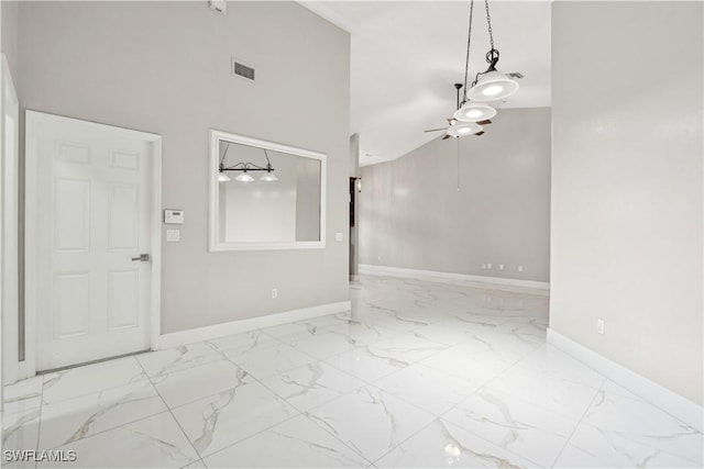 unfurnished room with a towering ceiling and ceiling fan