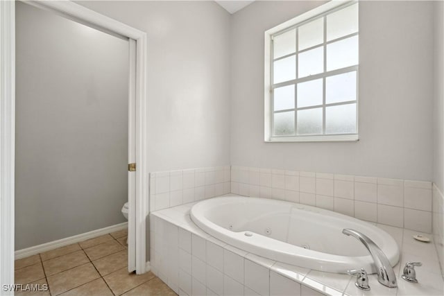 bathroom featuring a relaxing tiled tub, tile patterned floors, and toilet