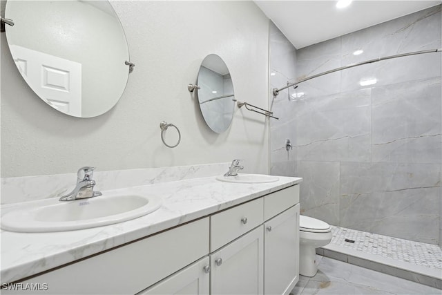 bathroom featuring vanity, a tile shower, and toilet