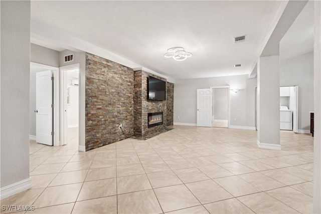 unfurnished living room with light tile patterned flooring, washer / dryer, and a fireplace