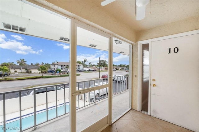 doorway with tile patterned flooring and ceiling fan