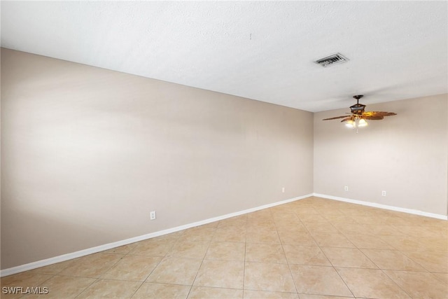 spare room featuring ceiling fan, a textured ceiling, and light tile patterned floors