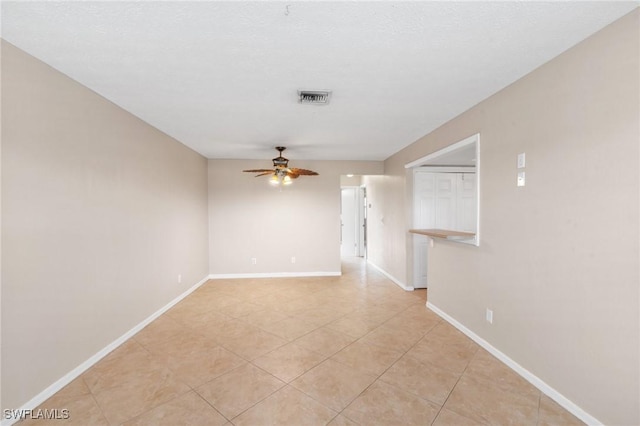 empty room with light tile patterned floors, a textured ceiling, and ceiling fan