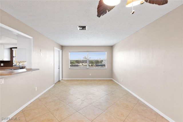 spare room featuring sink, light tile patterned floors, and a textured ceiling