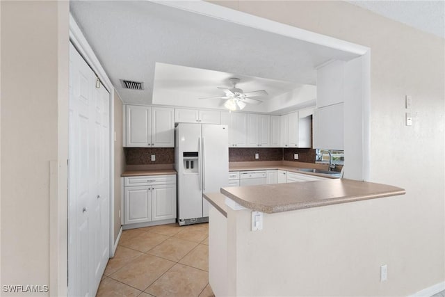 kitchen with white cabinetry, white appliances, kitchen peninsula, and sink